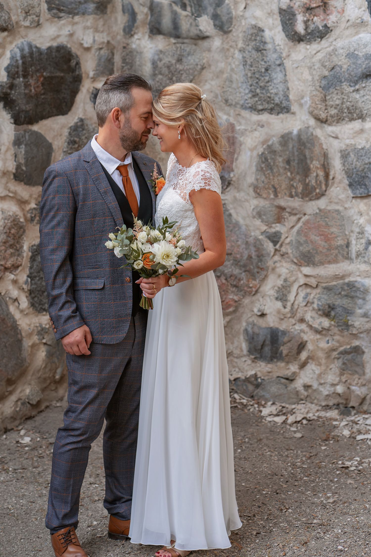 Maria och Håkan håller om varandra med brudbuketten vid S:t Olofs ruin i Sigtuna.