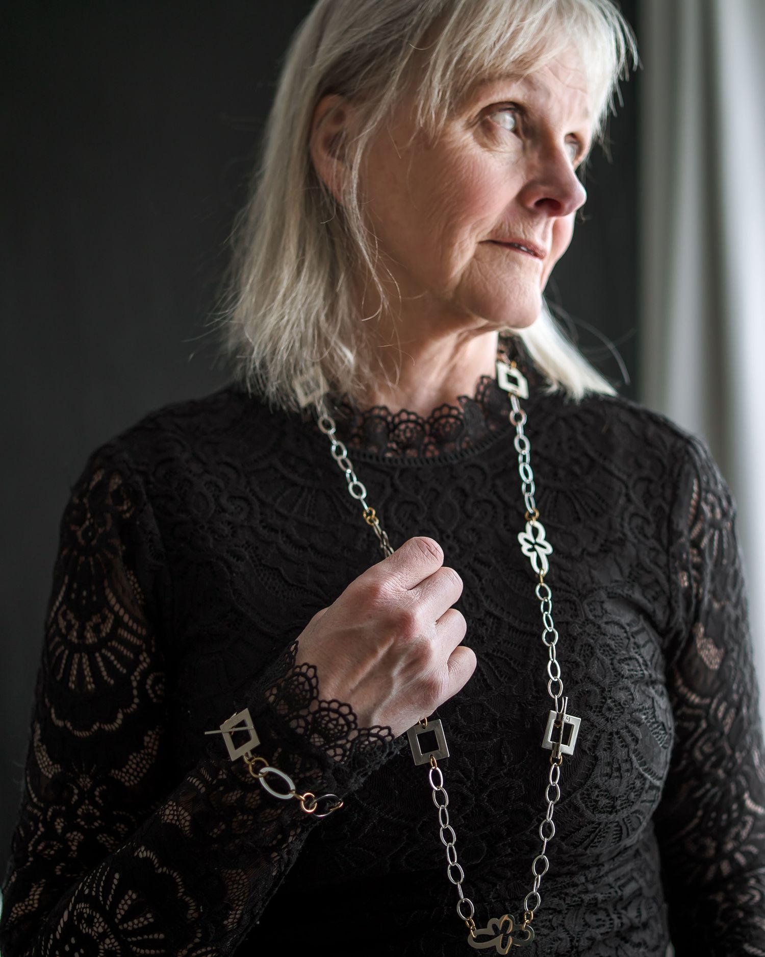 A person wearing a black lace top and silver chain necklace is shown in a series of contemplative poses.
