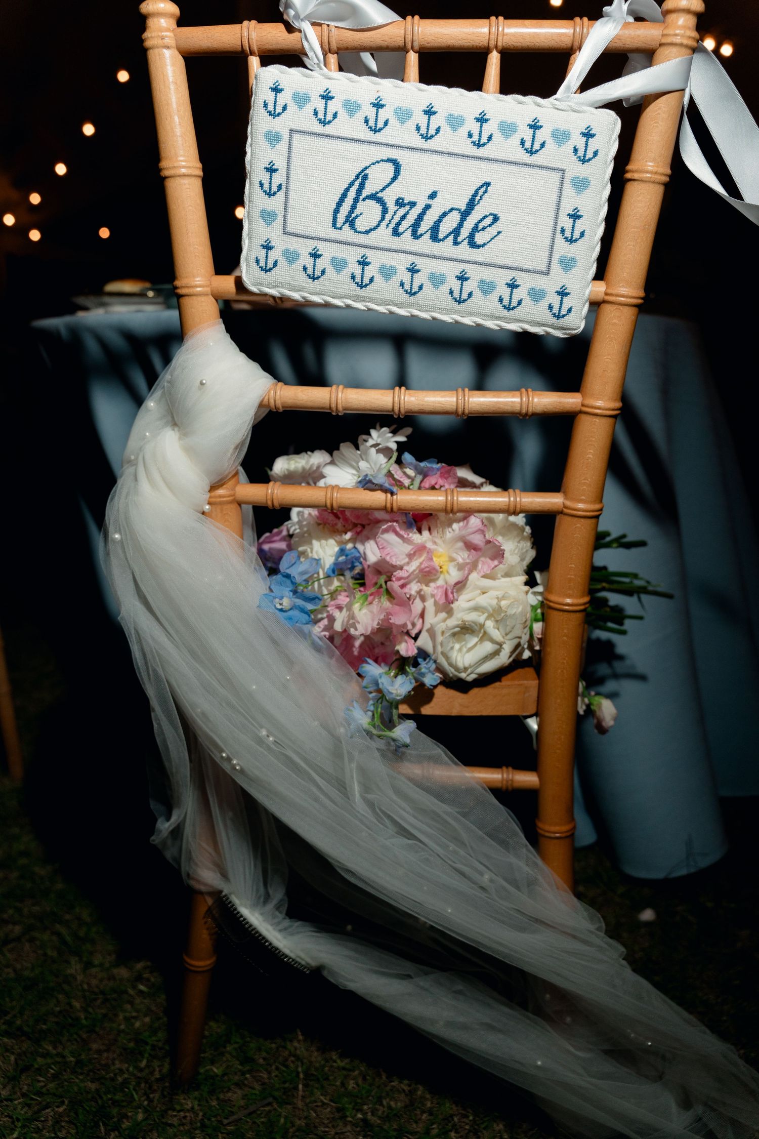 Bride chair sign with nautical anchor design holding bridal bouquet of pink, blue, and white flowers.