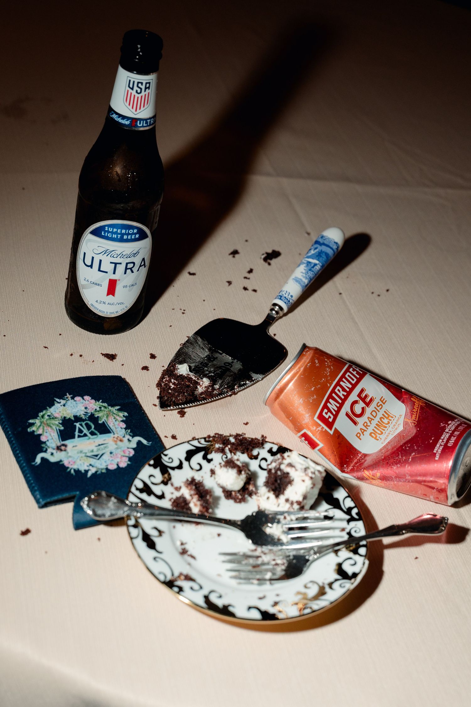 Wedding reception table with leftover cake, Michelob Ultra beer, Starburst Ice drink, and cake server.
