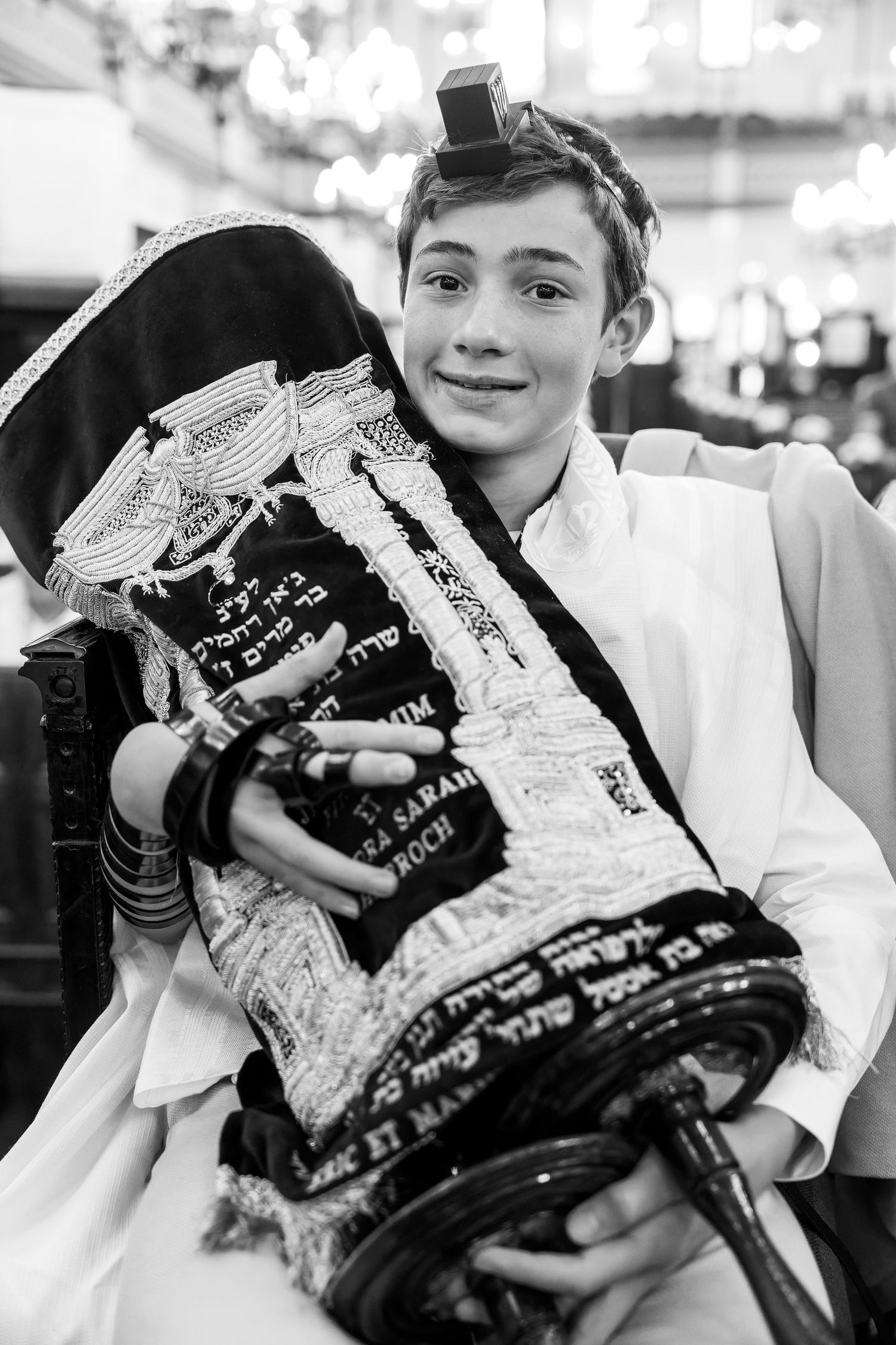 Black and white photo of a boy holding a Torah scroll during his Bar Mitzvah ceremony.