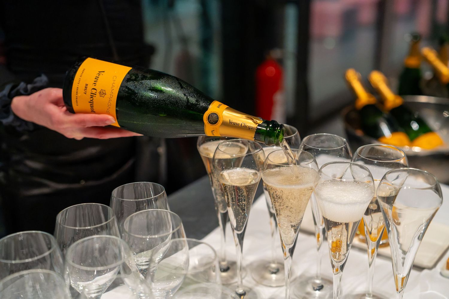 Bartender pouring Veuve Clicquot champagne into crystal flutes at an elegant event.