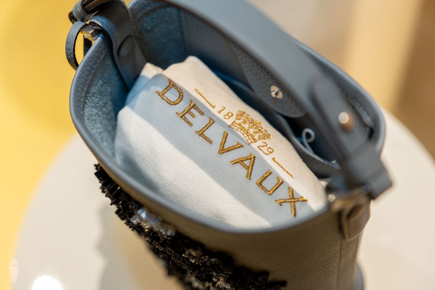 Interior view of a light blue Delvaux luxury leather handbag showing gold embossed brand logo.