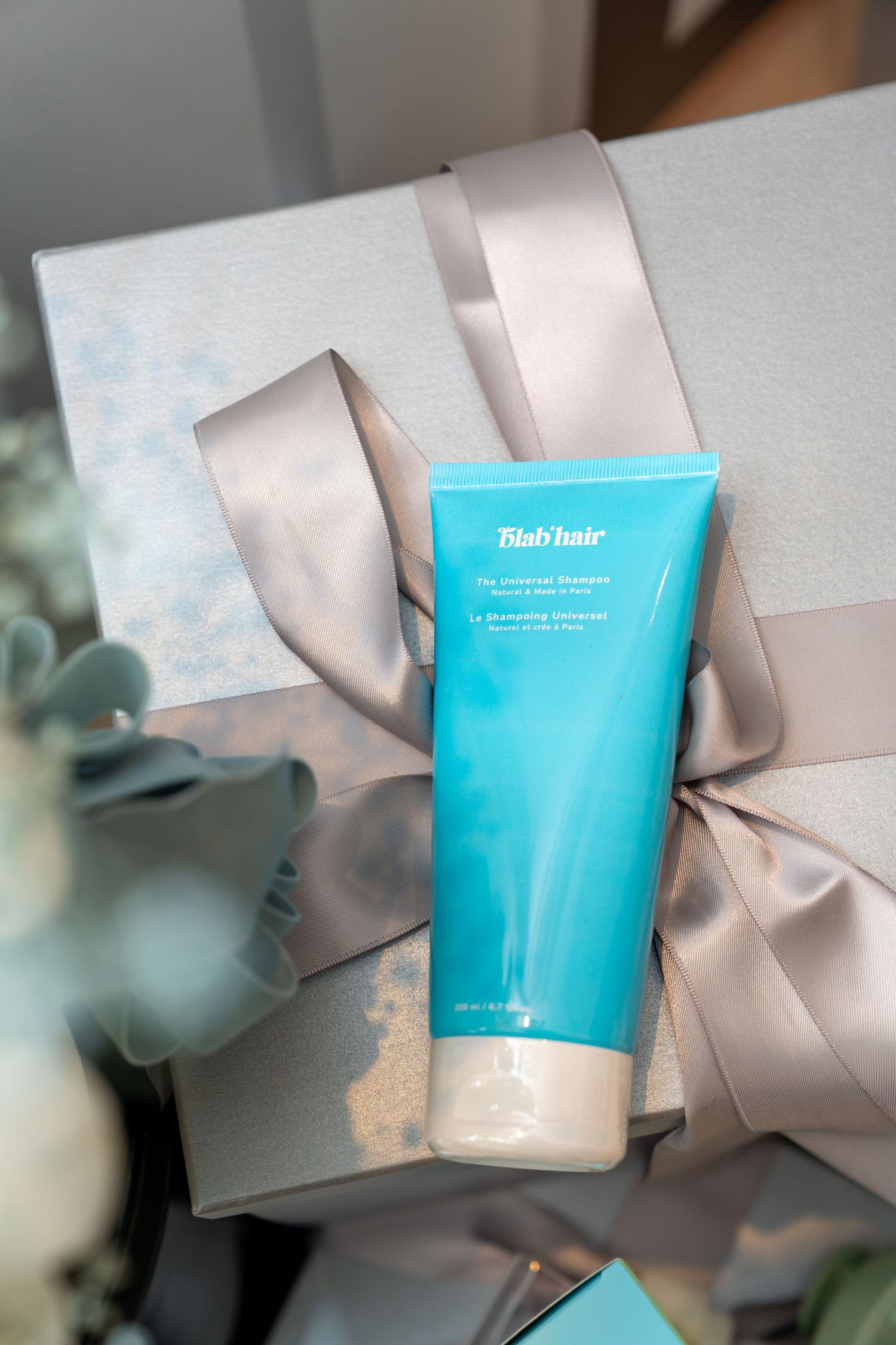 Blab Hair universal shampoo tube placed on a silver gift box with satin ribbon bow.