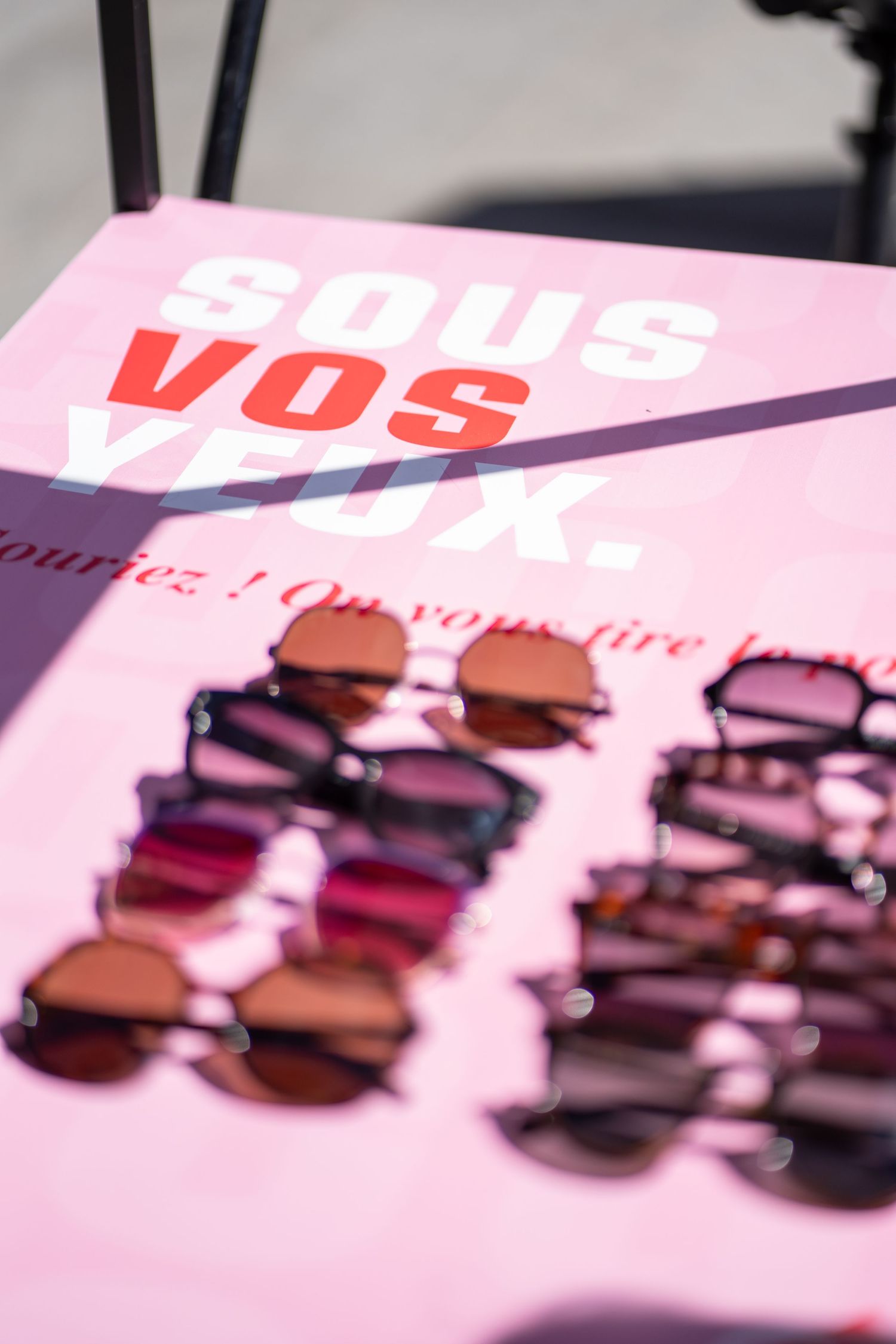 Sunglasses displayed on a pink surface with bold French text 