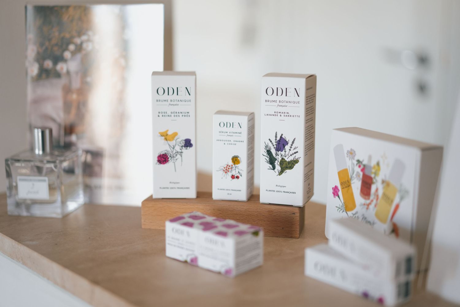 Odea natural skincare product collection displayed on wooden shelf with floral packaging.