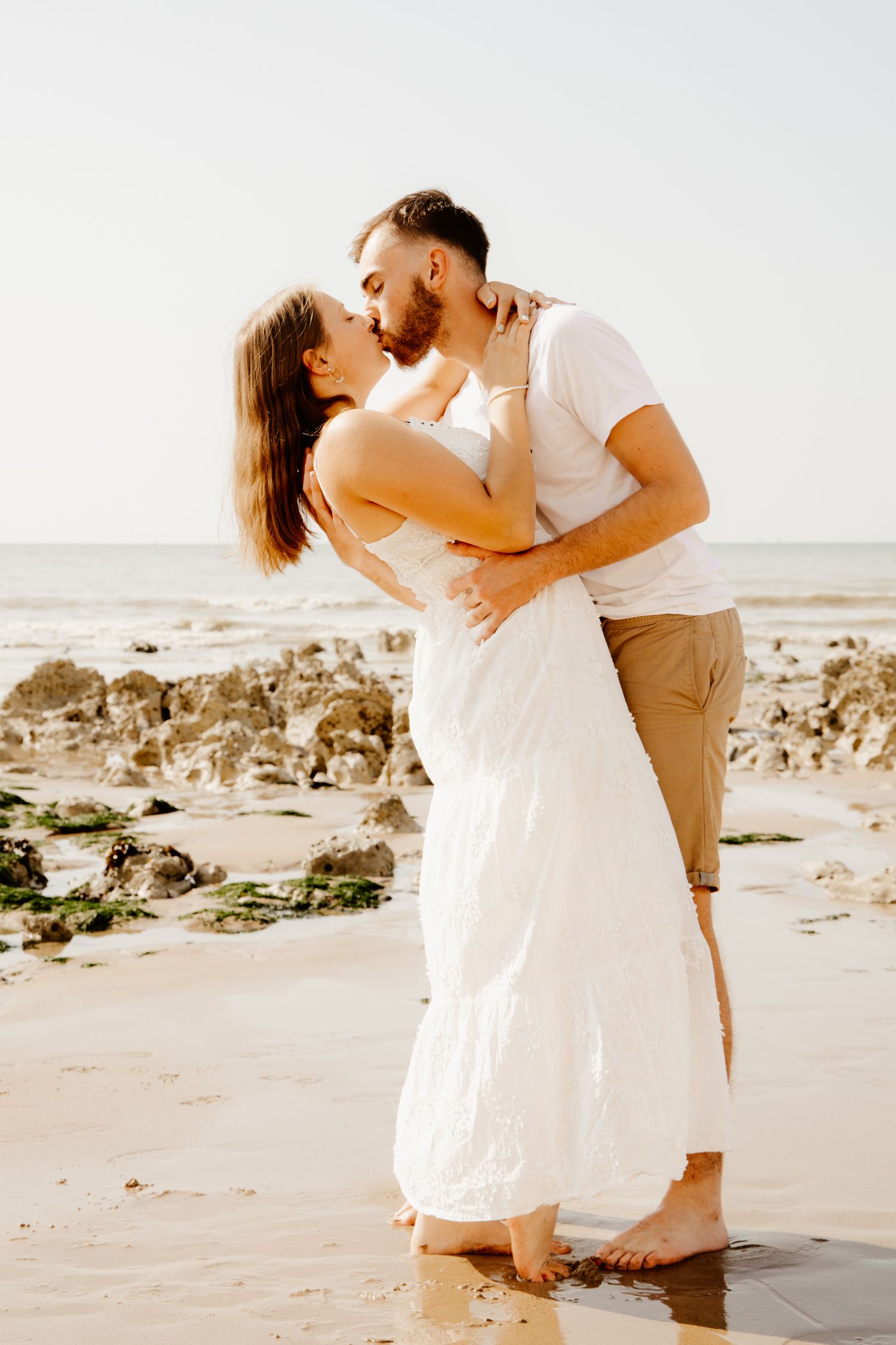 couple qui se fait un bisous sous les falaise e bord de mer pendant une séance photo couple