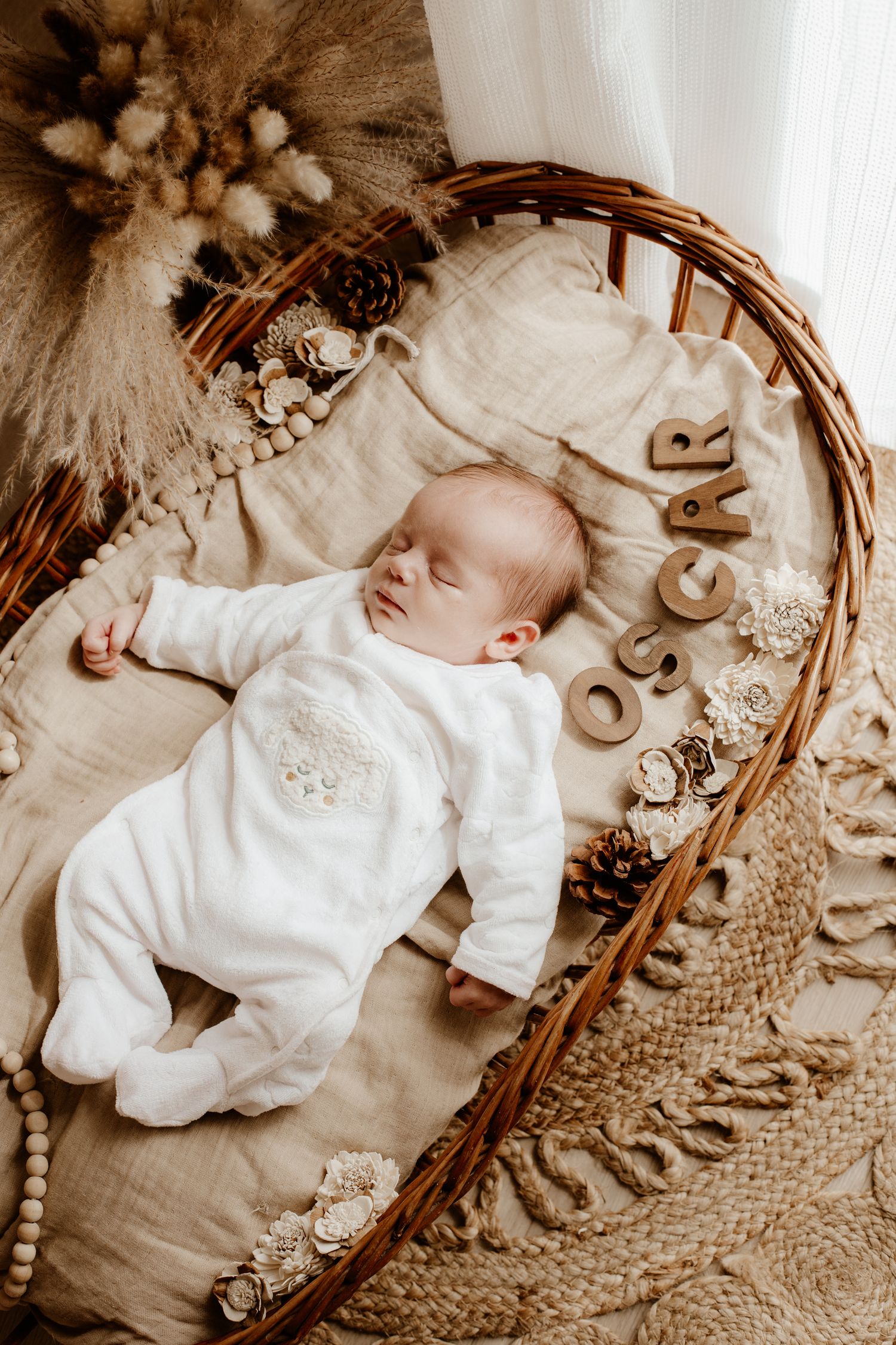 bébé qui dort paisiblement dans un couffin bohème pendant une séance photo nouveau-né