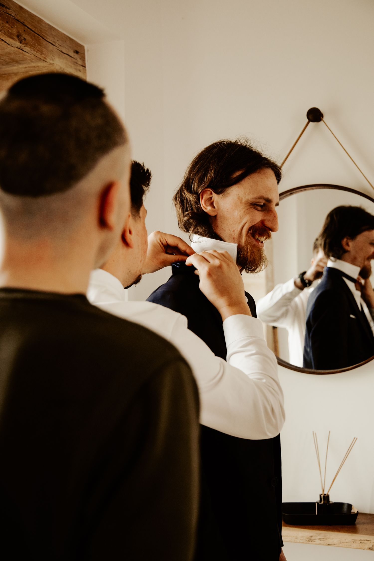 Les garçons d’honneur aident à ajuster le nœud papillon du marié pendant ses préparatifs de mariage.