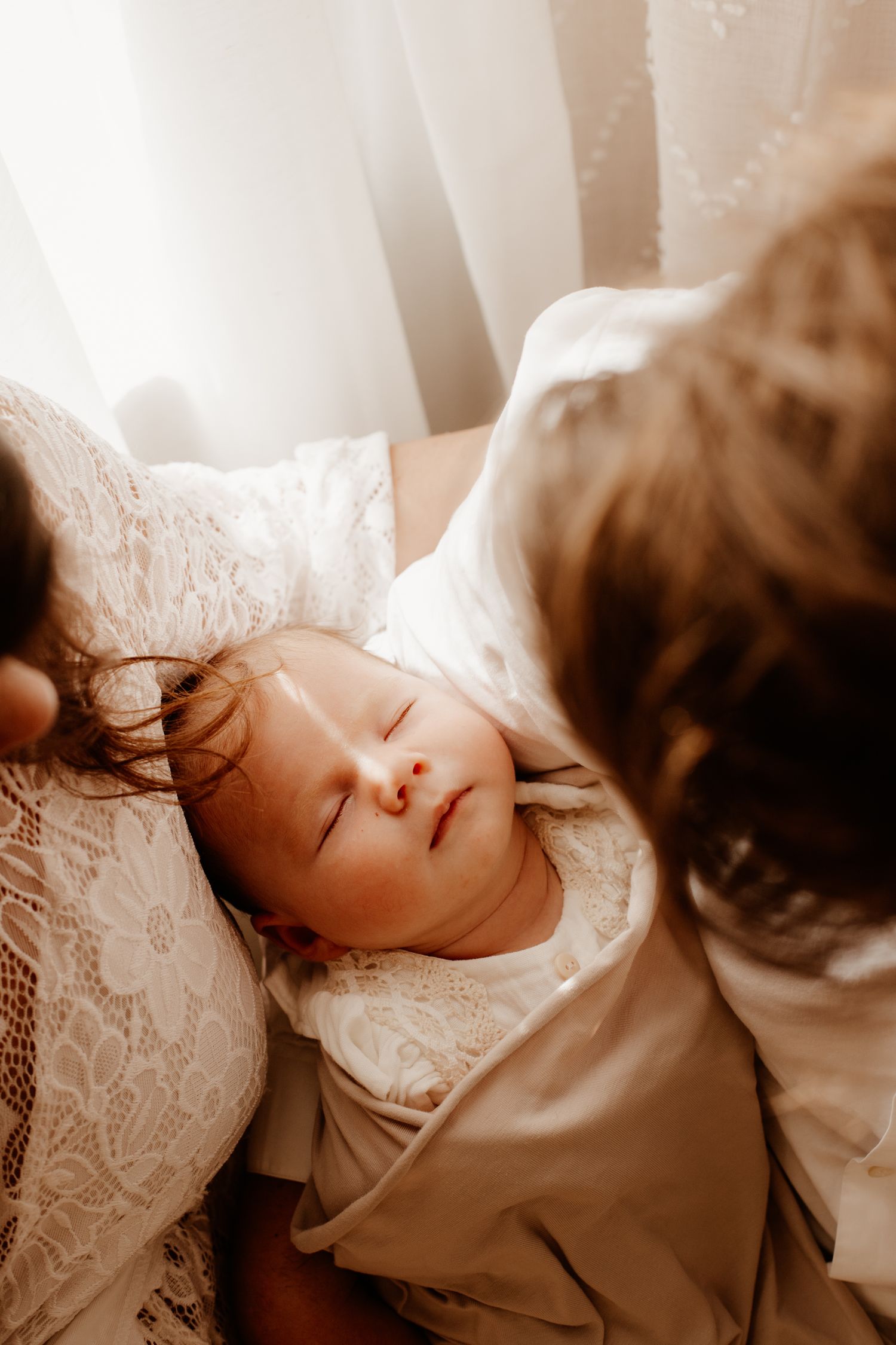 nouveau-né qui dort dans le bras de ses parents pendant une séance photo naissance
