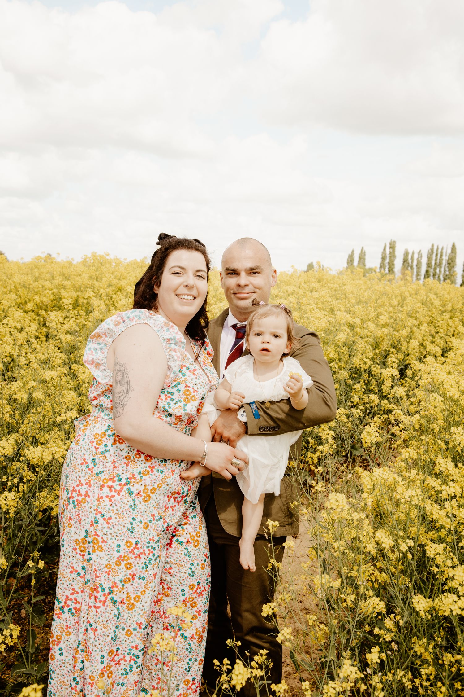 photo de famille d'un couple et d'un bébé dans un champs de colza