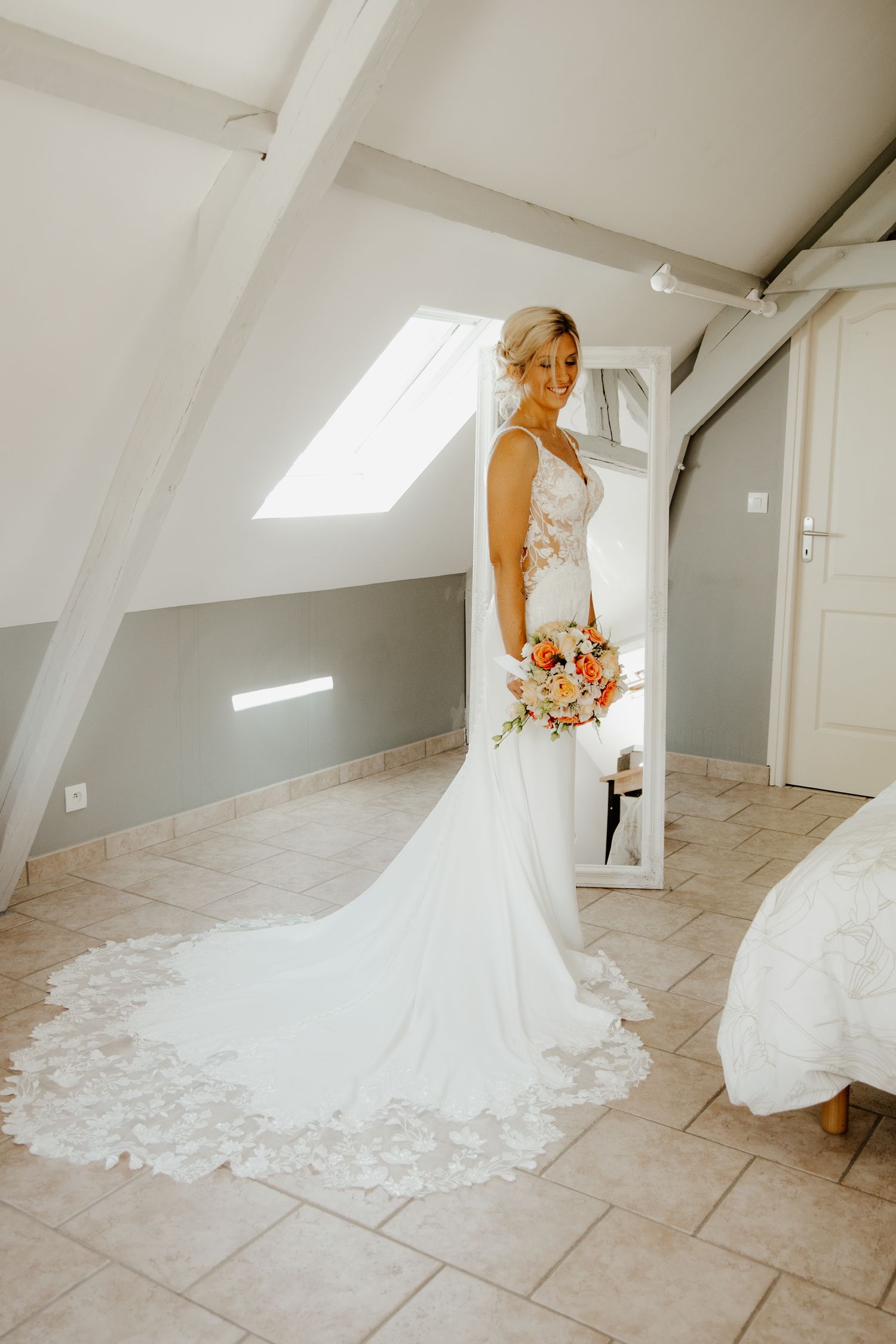 Portrait en pied de la mariée de dos, mettant en valeur la longue traîne de sa robe blanche.