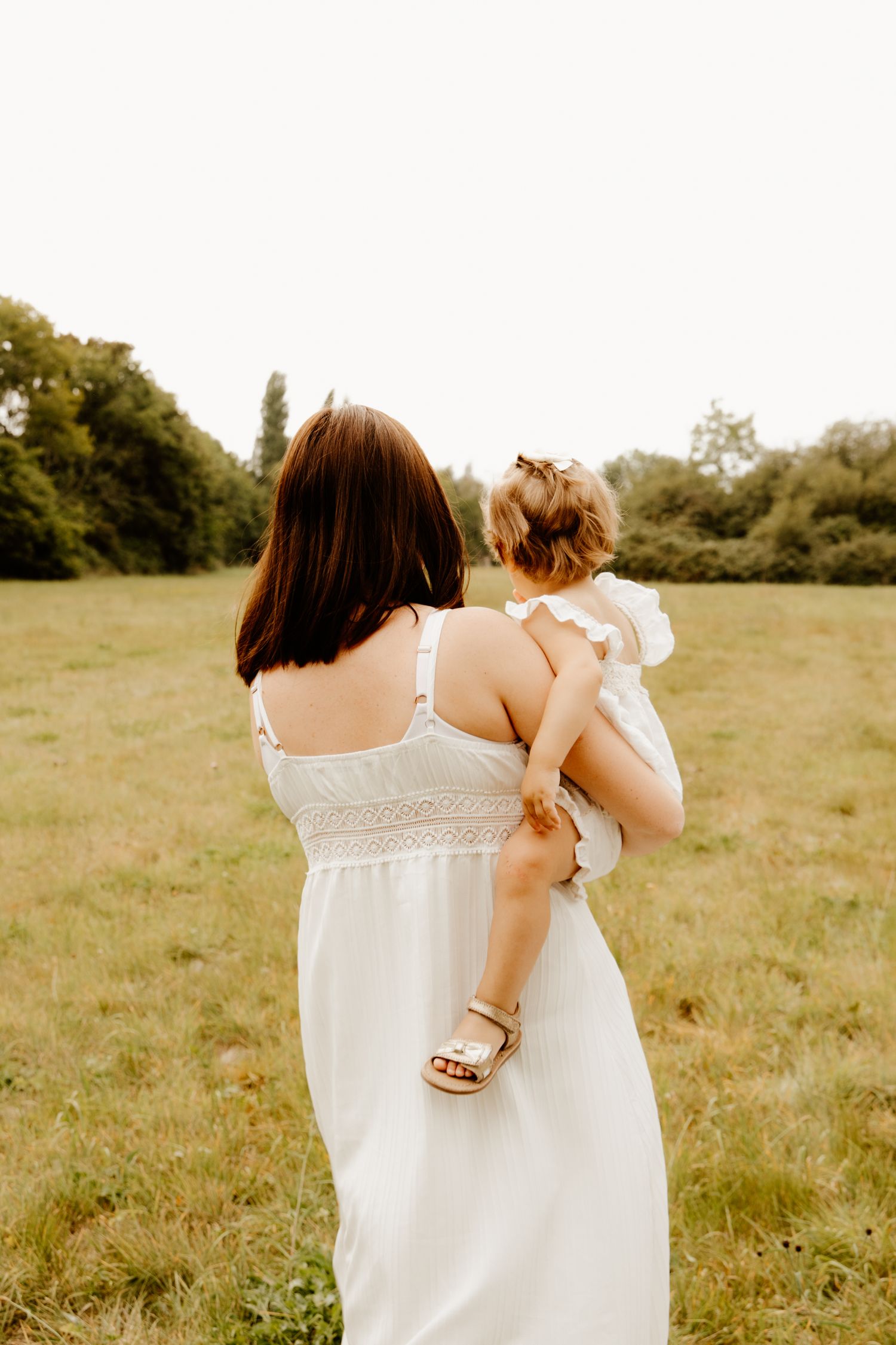 un mère qui tien dans ses bras sa fille dans un champs pendant une séance photo famille
