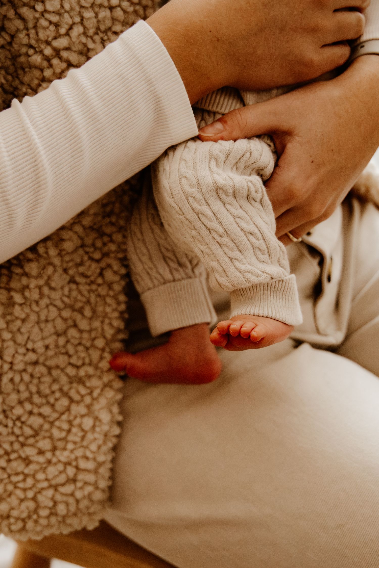 Gros plan poétique sur le petit pied d'un nouveau-né blotti dans les bras de sa maman. Séance photo bébé et maternité.