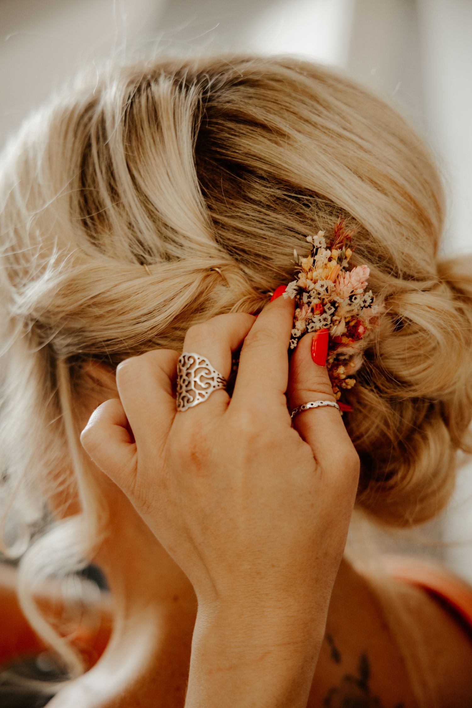 Portrait intime de profil de la mariée touchant discrètement ses cheveux pendant sa coiffure de mariage.