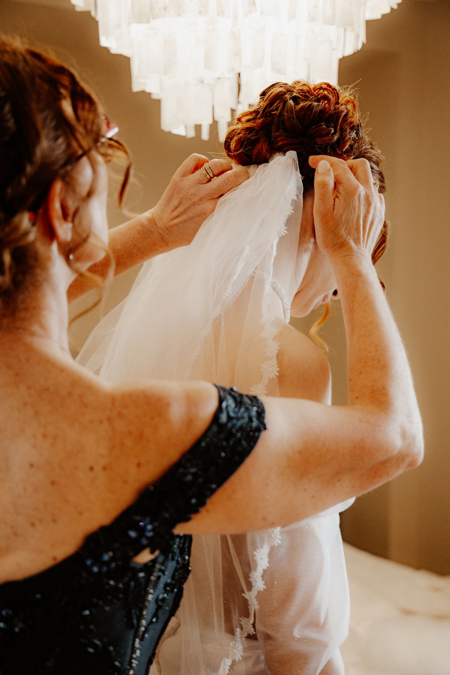 Moment d'émotion : la maman de la mariée ajuste délicatement son voile pendant les préparatifs avant la cérémonie.