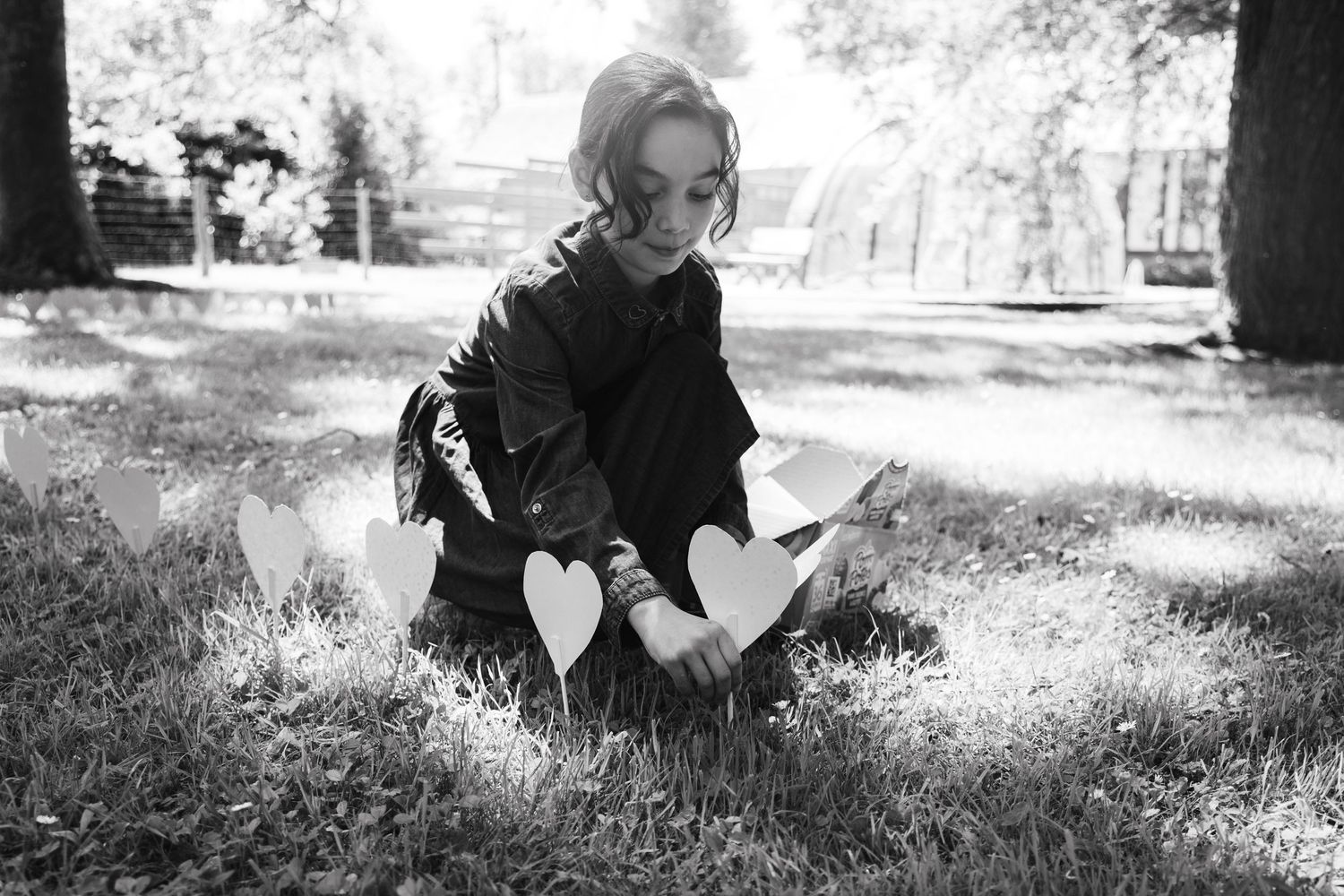 Photo de mariage artistique en noir et blanc de la mariée assise sur l'herbe d'un parc.