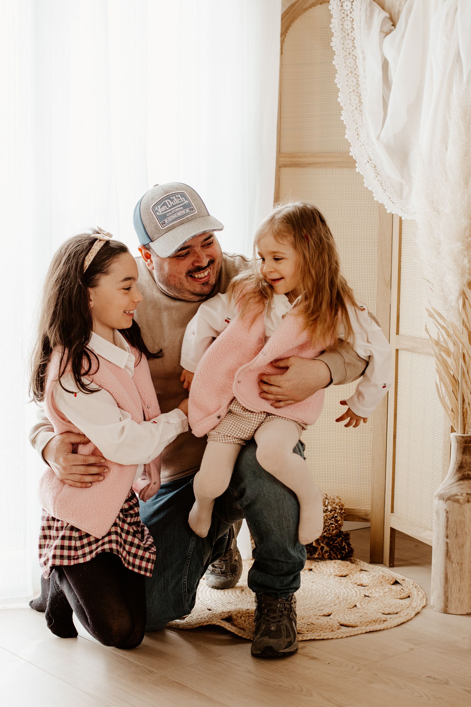 papa entouré de ses filles qui rigolent tout les 3 en faisant un câlin