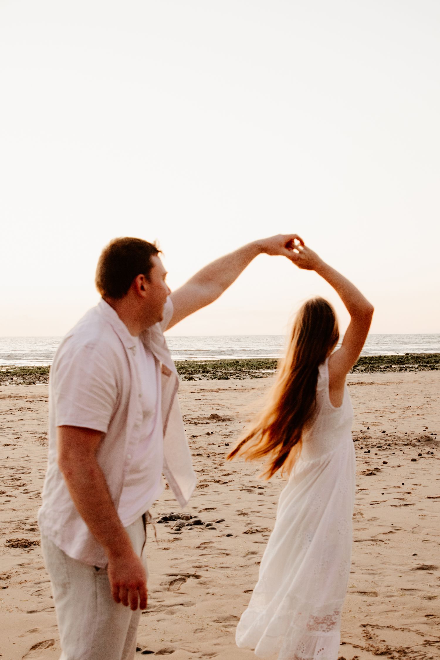 couple qui danse au bord de la mer sur la plage au couché du soleil