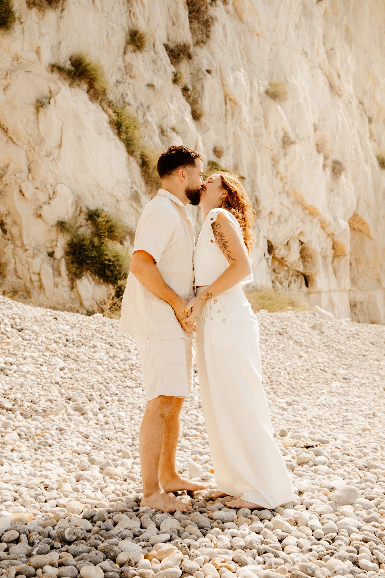couple qui se fait un bisous sous les falaise e bord de mer pendant une séance photo couple