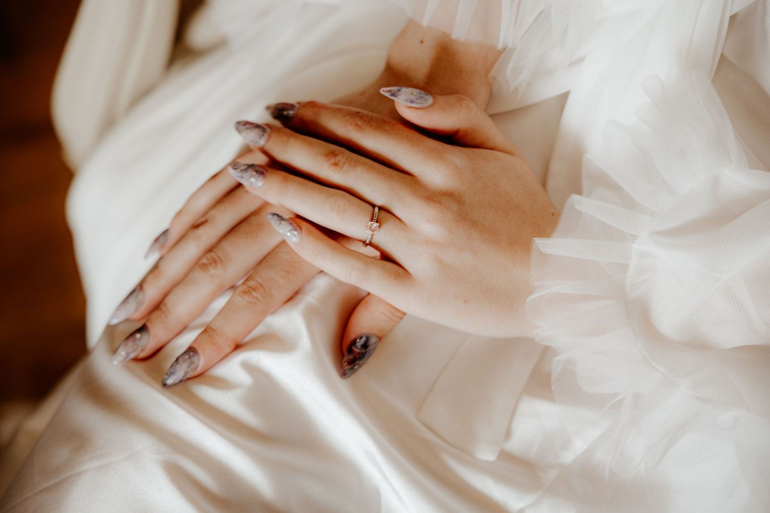Gros plan et détails sur les mains de la mariée, sa bague de fiançailles et sa robe en dentelle. Mariage élégant.
