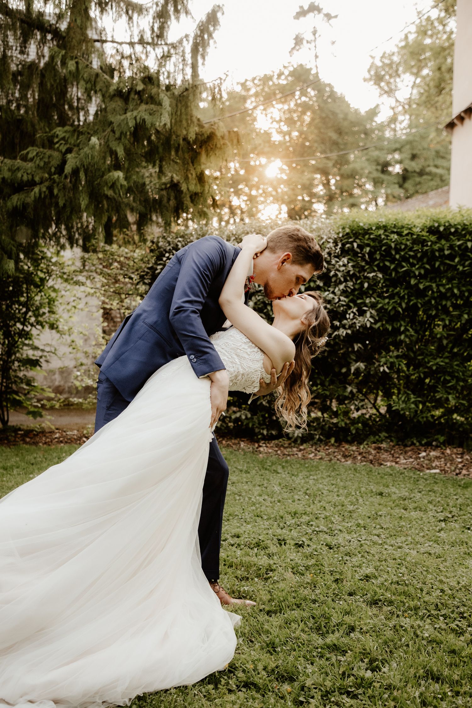 Baiser romantique de mariés au coucher du soleil en pleine nature. Séance photo de couple par votre photographe de mariage.