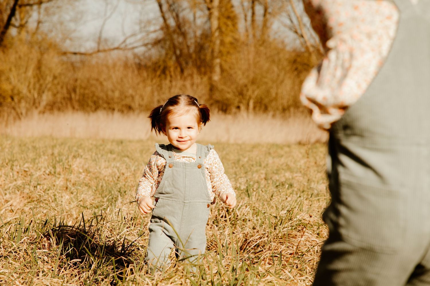 petite fille qui rigole dans un champs pendant une séance photo famille