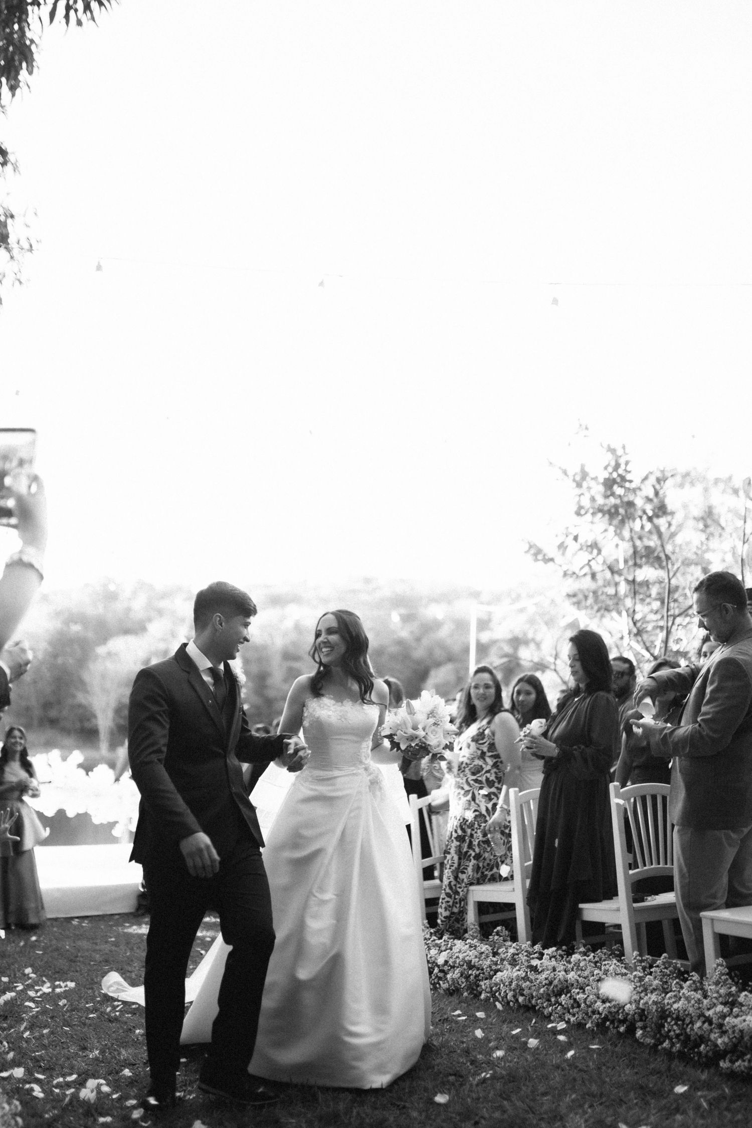 Black and white photo of joyful newlyweds walking back down the aisle after ceremony.