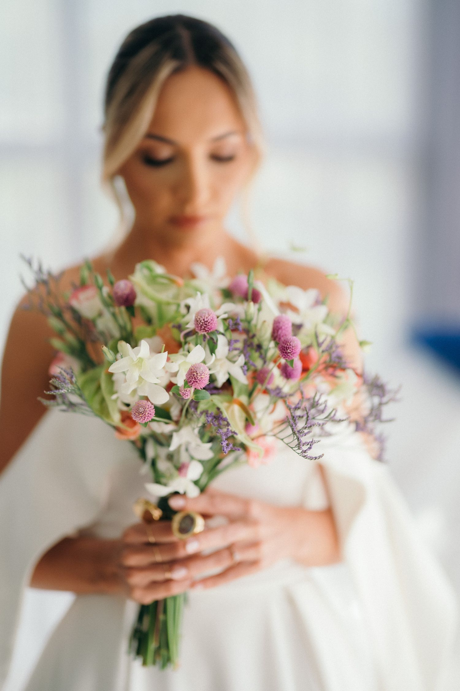 Bride in white strapless gown holding a colorful wildflower bouquet with pink and white blooms.