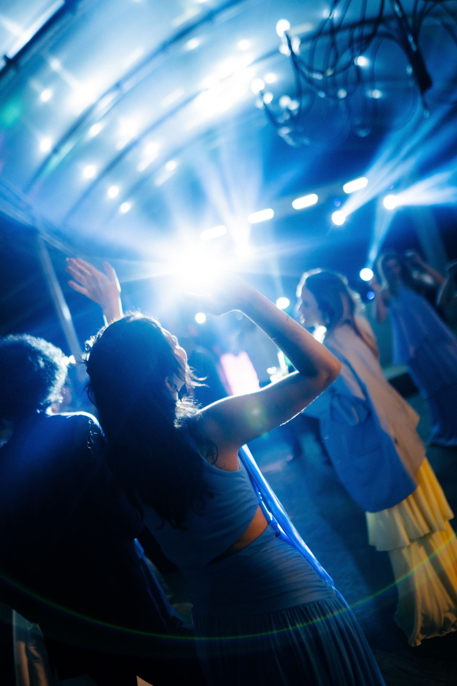 Guests dancing under blue stage lights at a lively wedding reception party.