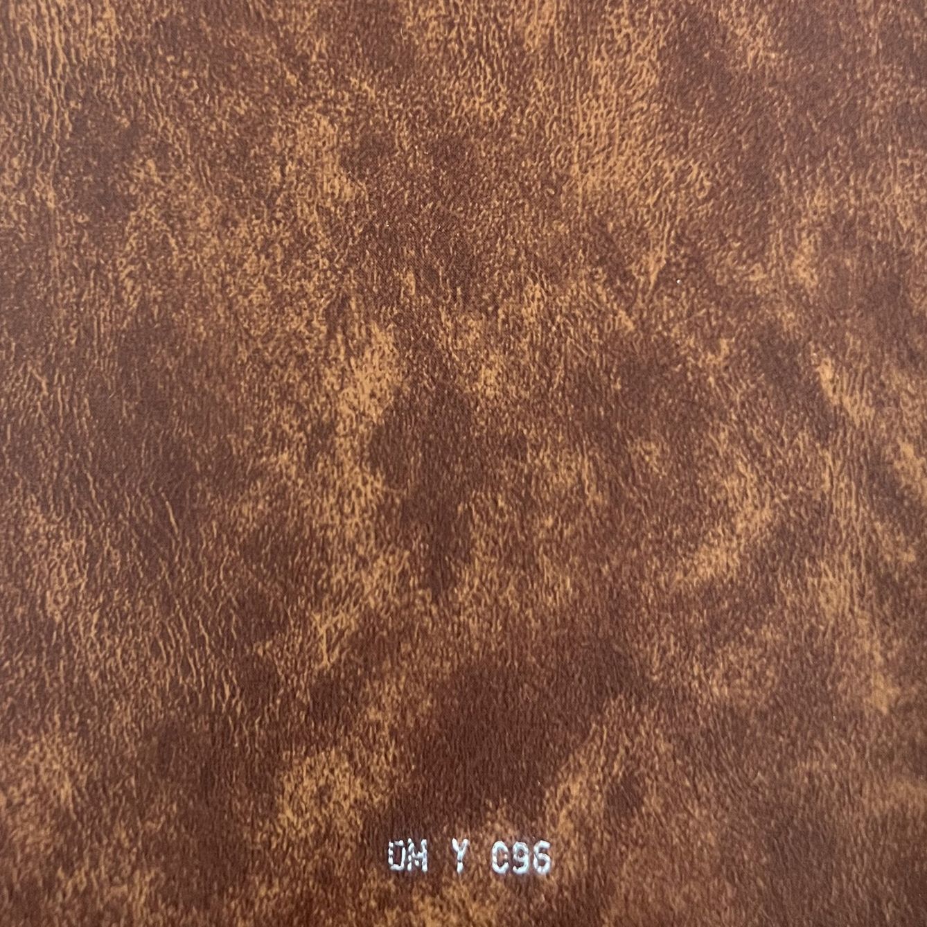 Close-up of warm brown distressed leather texture fabric swatch labeled DM Y 096.