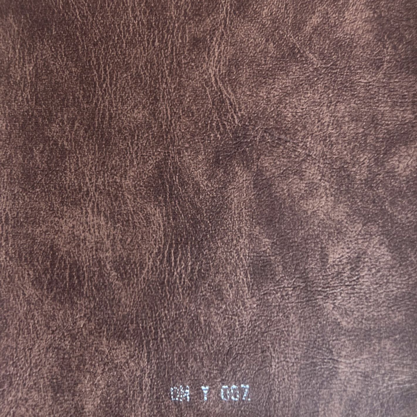 Close-up of brown distressed leather texture fabric swatch labeled DM Y 007.