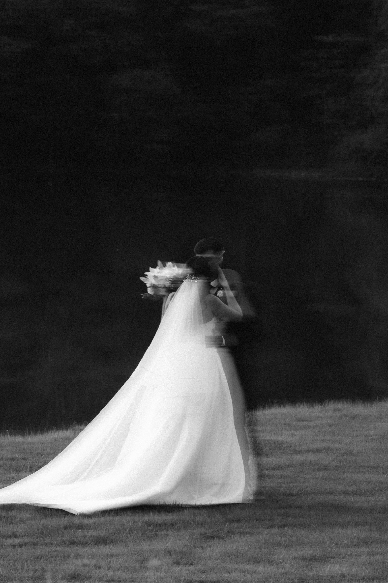 Artistic blurred black and white photo of bride and groom embracing on wedding day.