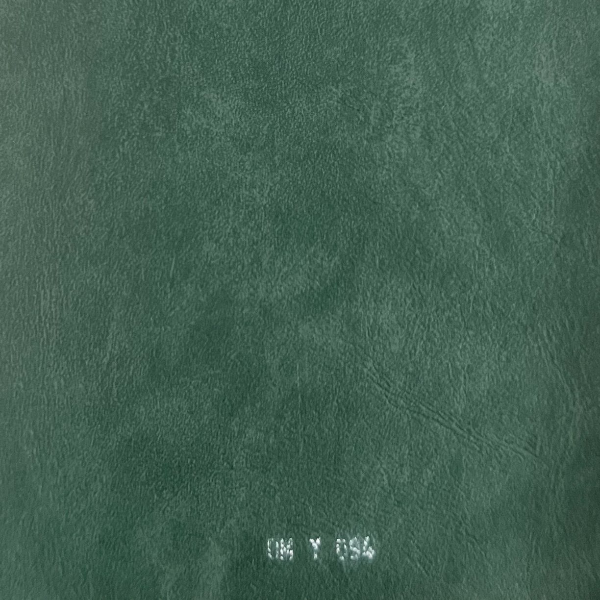 Close-up of deep green distressed leather texture fabric swatch labeled DM Y 054.