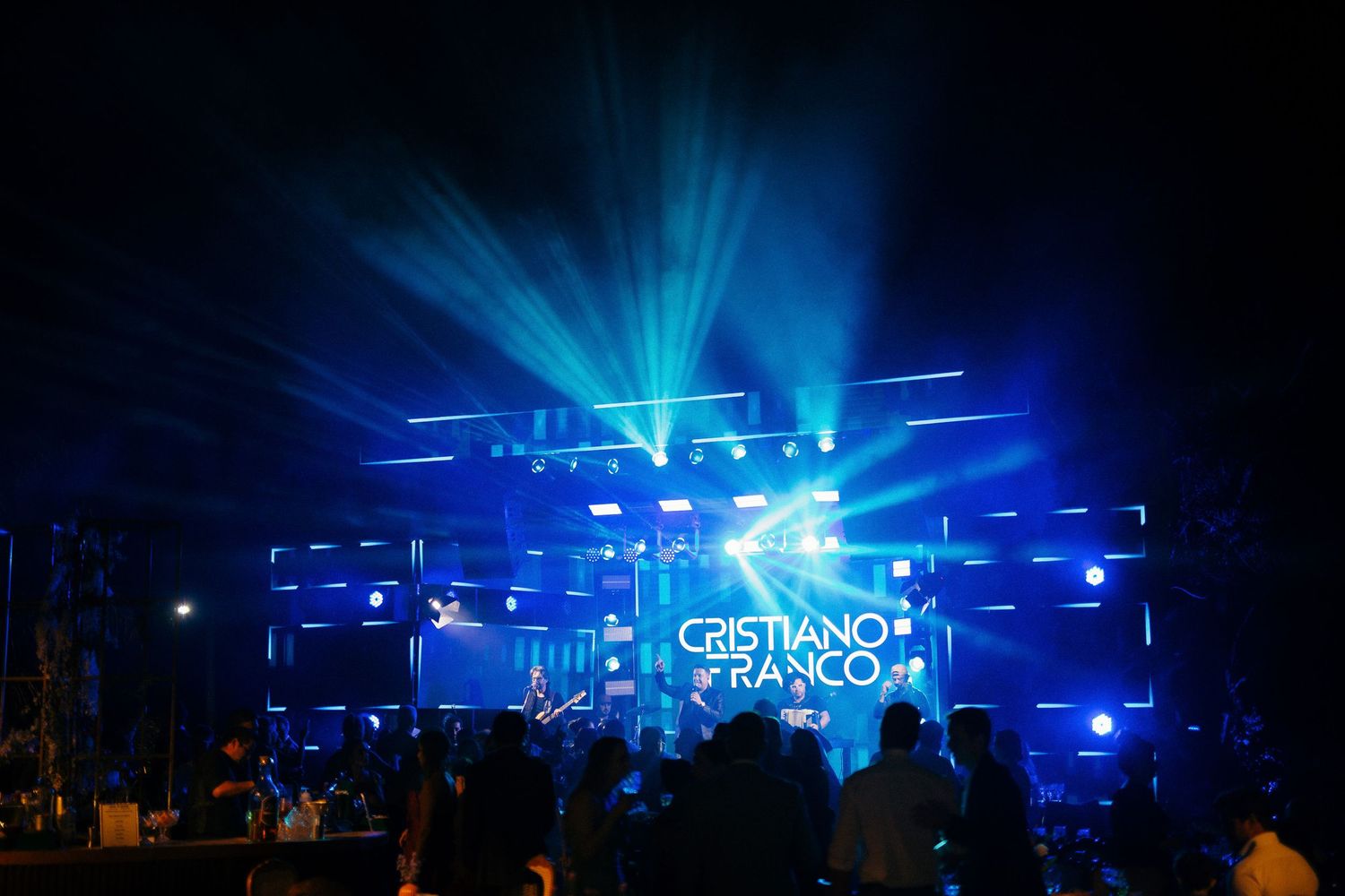 Cristiano Franco performs on stage with dramatic blue laser light show at night concert event.