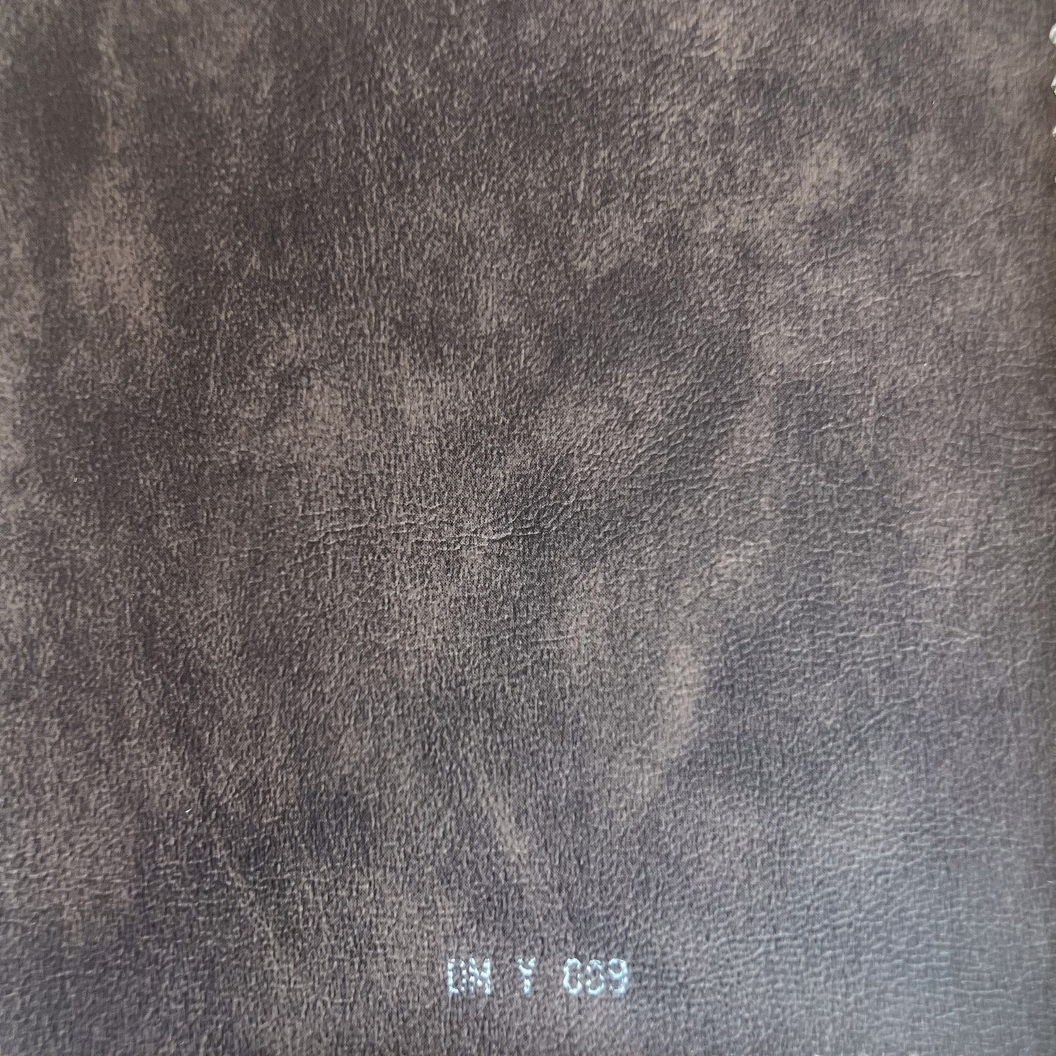 Close-up of dark charcoal gray distressed leather texture fabric swatch labeled DM Y 039.