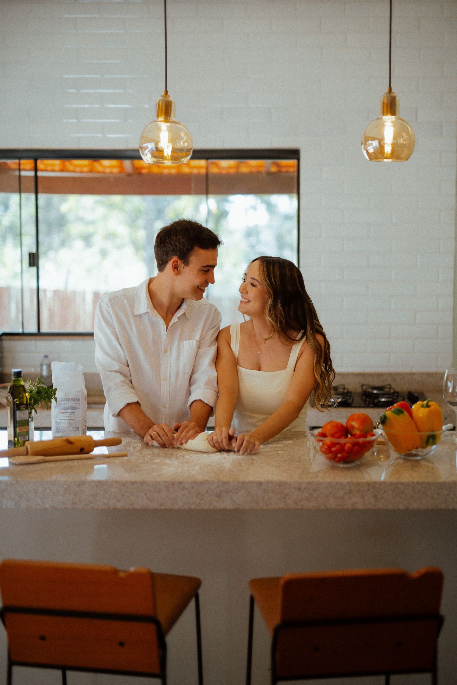 Happy couple sharing romantic moment at kitchen island with fresh vegetables and warm pendant lighting.