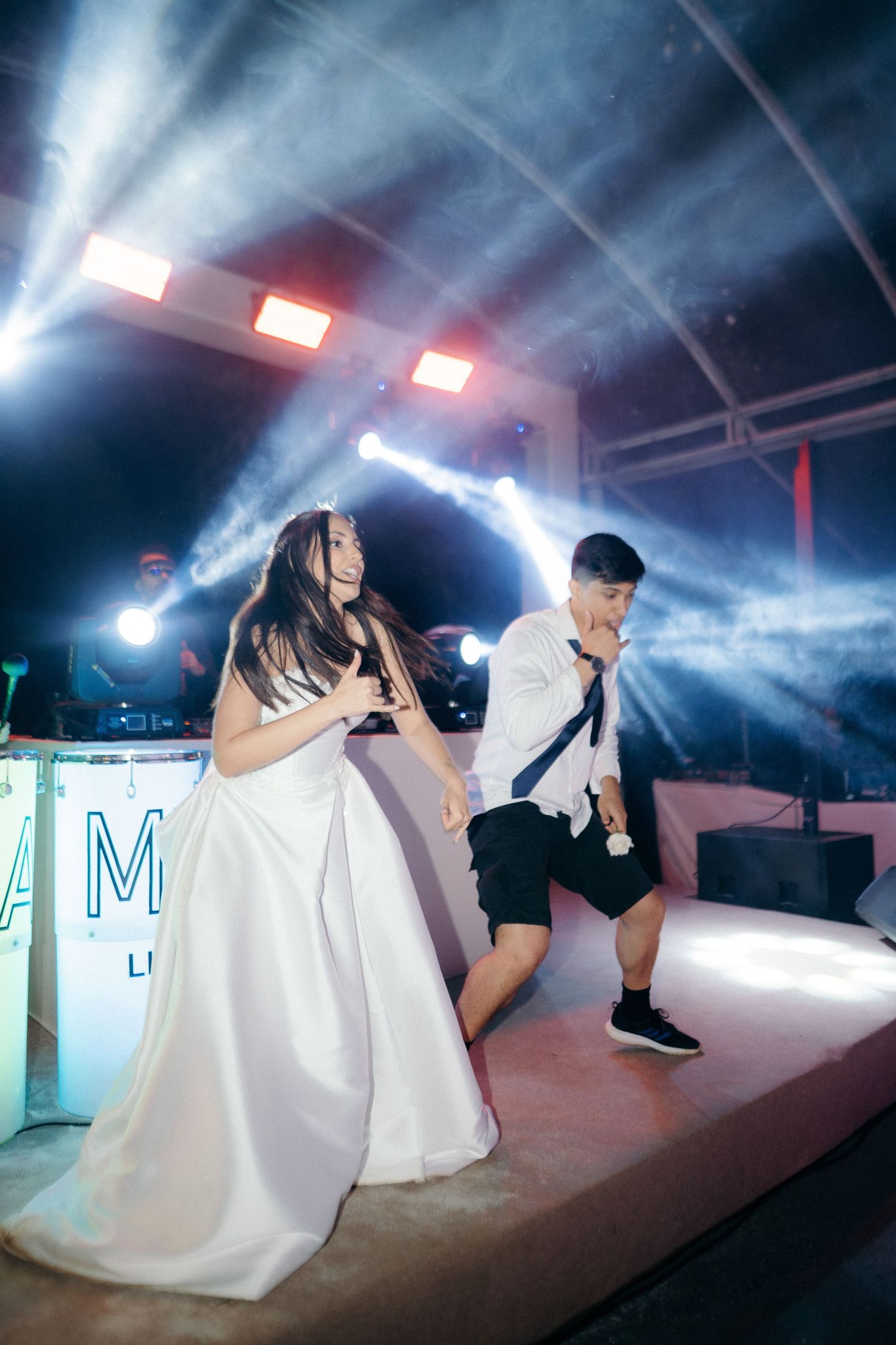 Bride and groom performing on stage with dramatic lighting and fog effects at a wedding reception celebration.