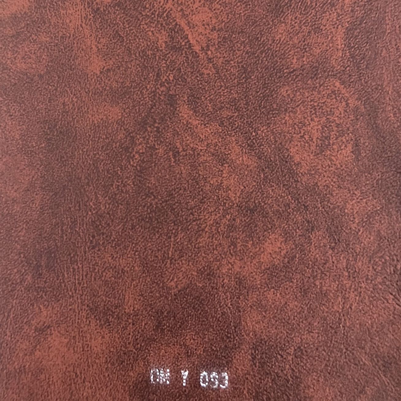 Close-up of rich reddish-brown distressed leather texture fabric swatch labeled DM Y 093.