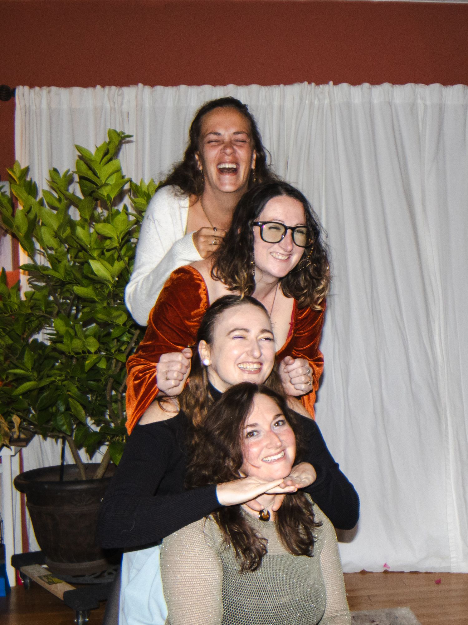 JCPenny Style photo. Four young women stacking and posing together, laughing and having fun indoors near a potted plant.