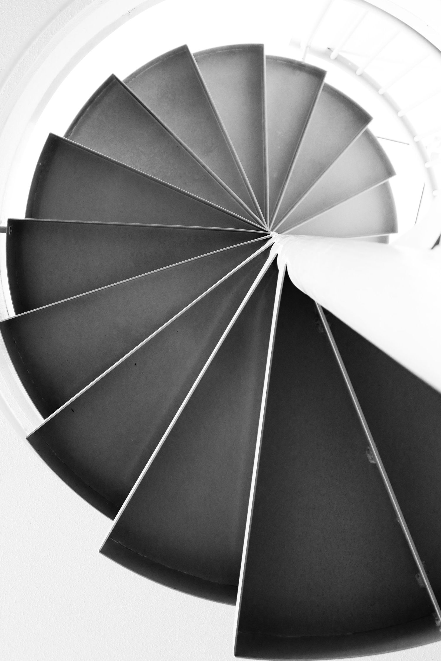 Black and white aerial view of a geometric spiral staircase with elegant curved steps.