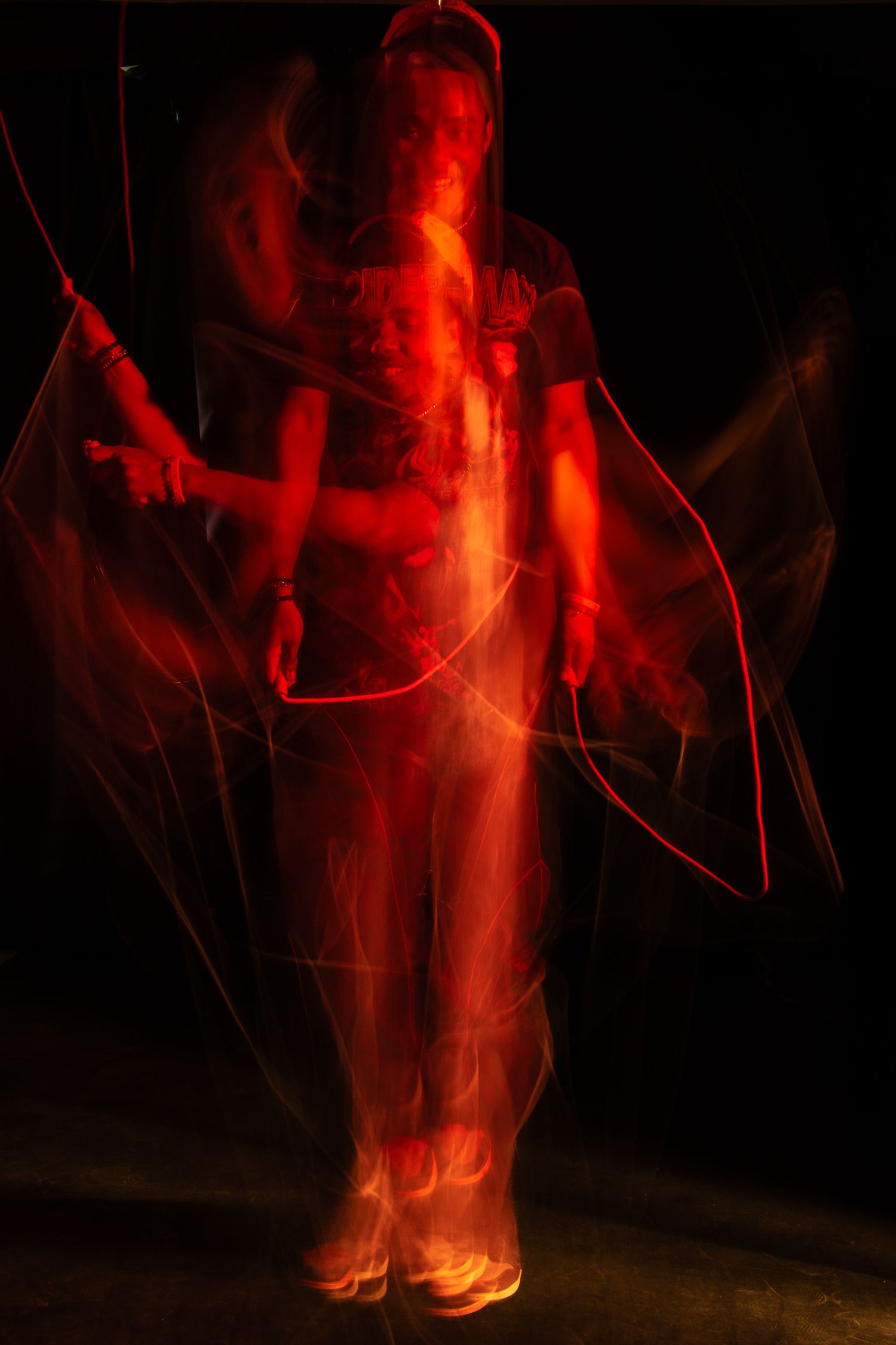 Long exposure photo of a person surrounded by red light trails against a dark background.