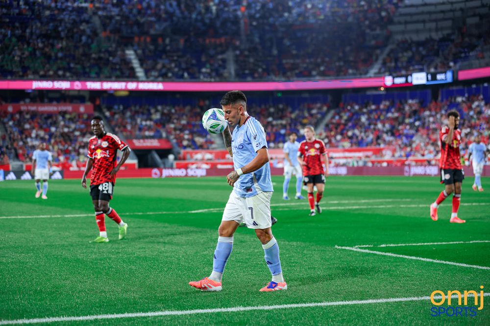 Soccer player in light blue jersey controls the ball during an MLS match in a packed stadium.