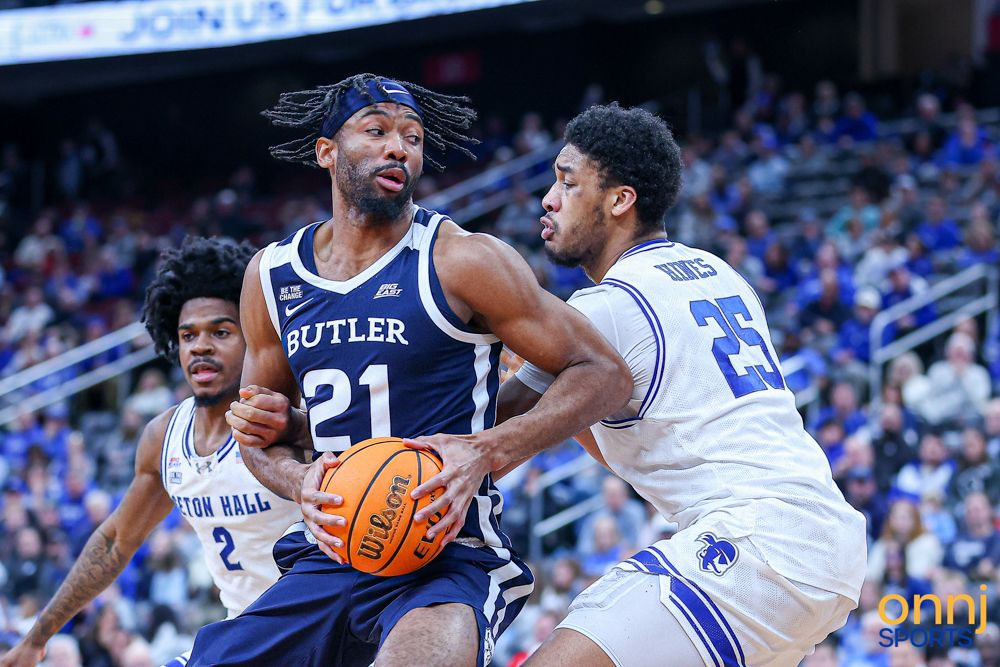 Butler #21 battles Seton Hall #25 for position during a physical college basketball game.