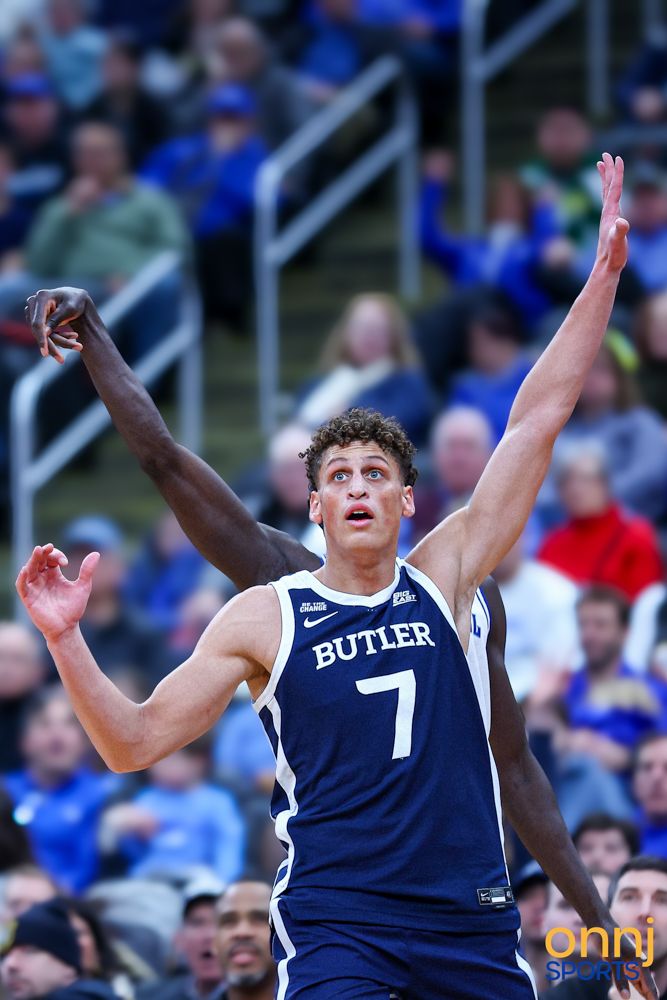 Butler University basketball player #7 raises arms wide open during an intense college basketball game.