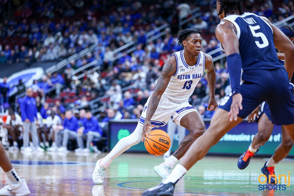 Seton Hall basketball player #13 dribbles drives toward the basket during a competitive college game.
