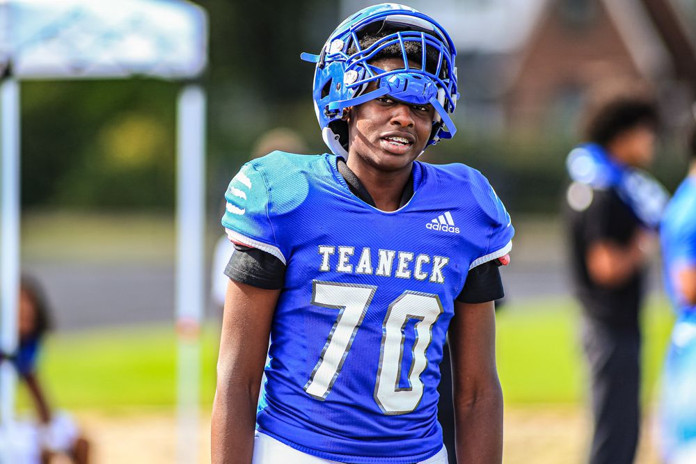 Teaneck high school football player number 70 in blue uniform and helmet standing on sideline during game.