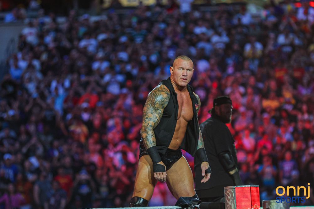 Tattooed WWE wrestler Randy Orton poses dramatically in the ring during a live event before a packed arena crowd.
