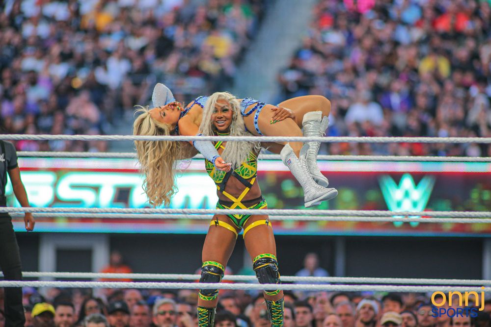 Two female WWE wrestlers grapple in the ring at SummerSlam with crowd in background.