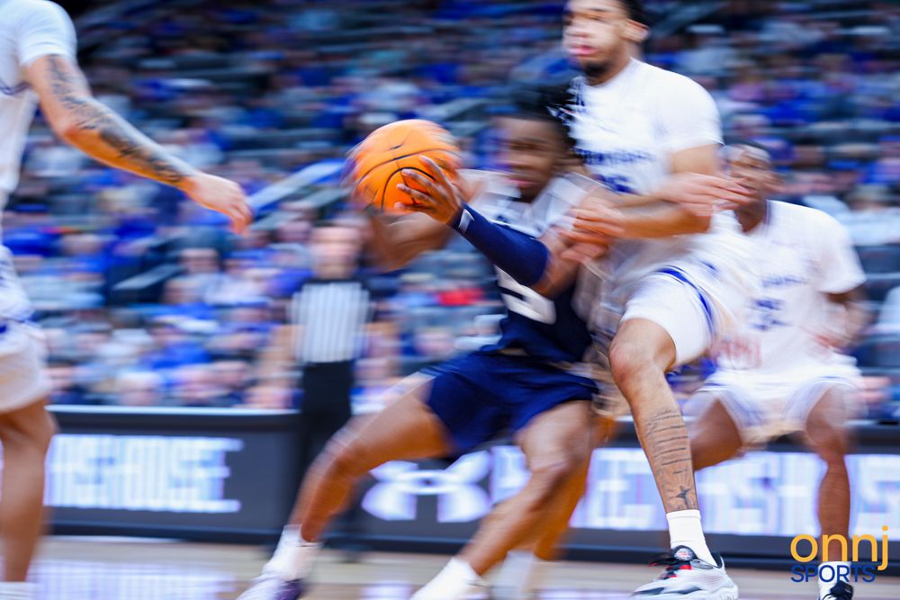 Motion-blurred basketball player drives to the basket during an intense college basketball game.